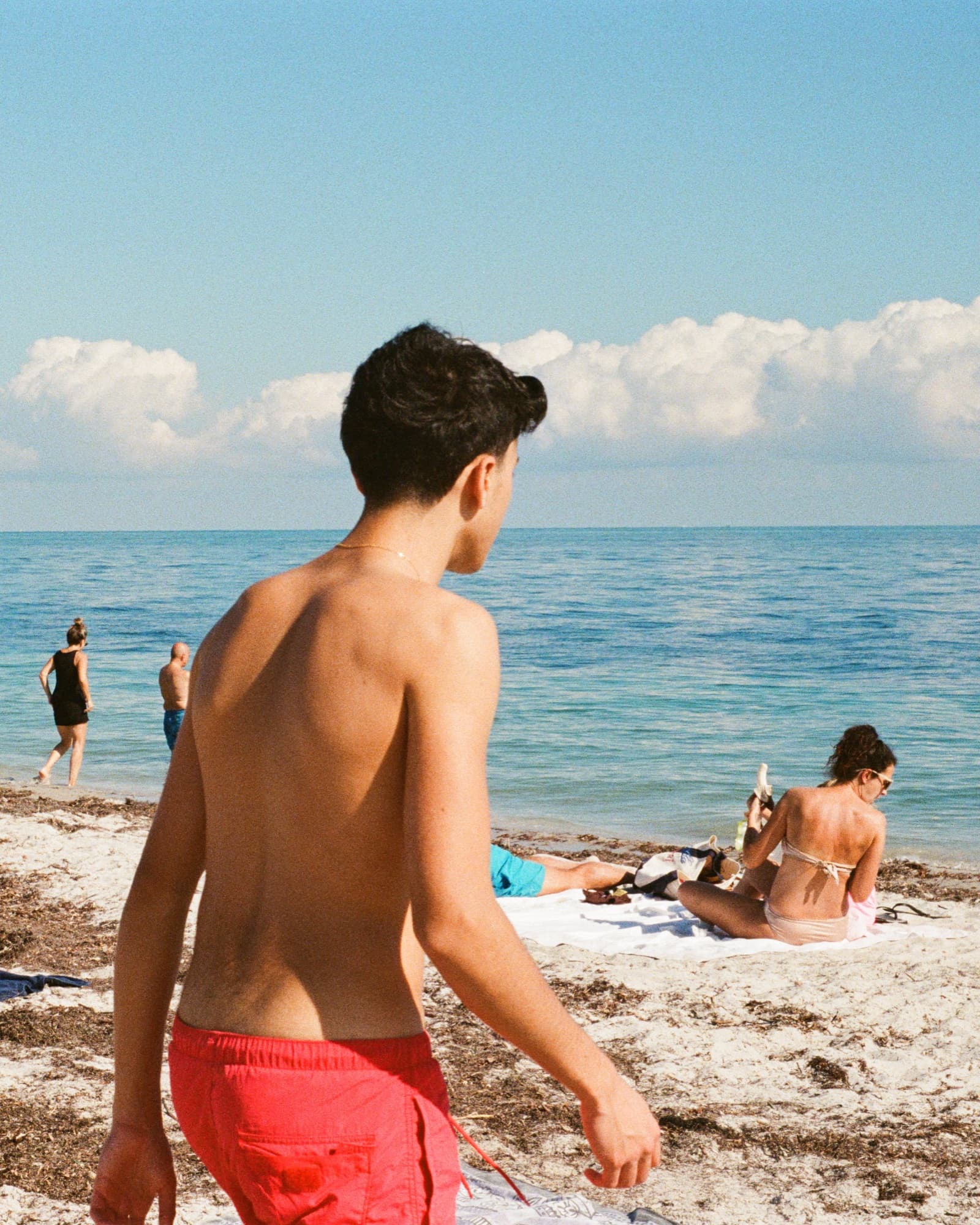 Film frame on Kodak Portra 800 — a beachgoer in red trunks at the shoreline, Miami Beach